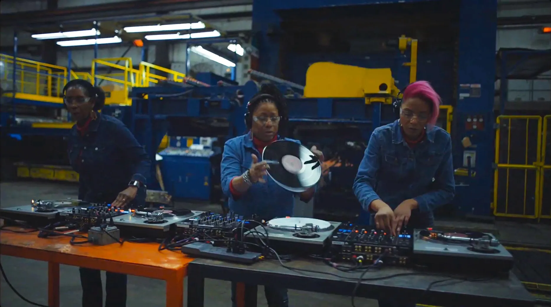 Three women dj on cdjs in a factory in Detroit