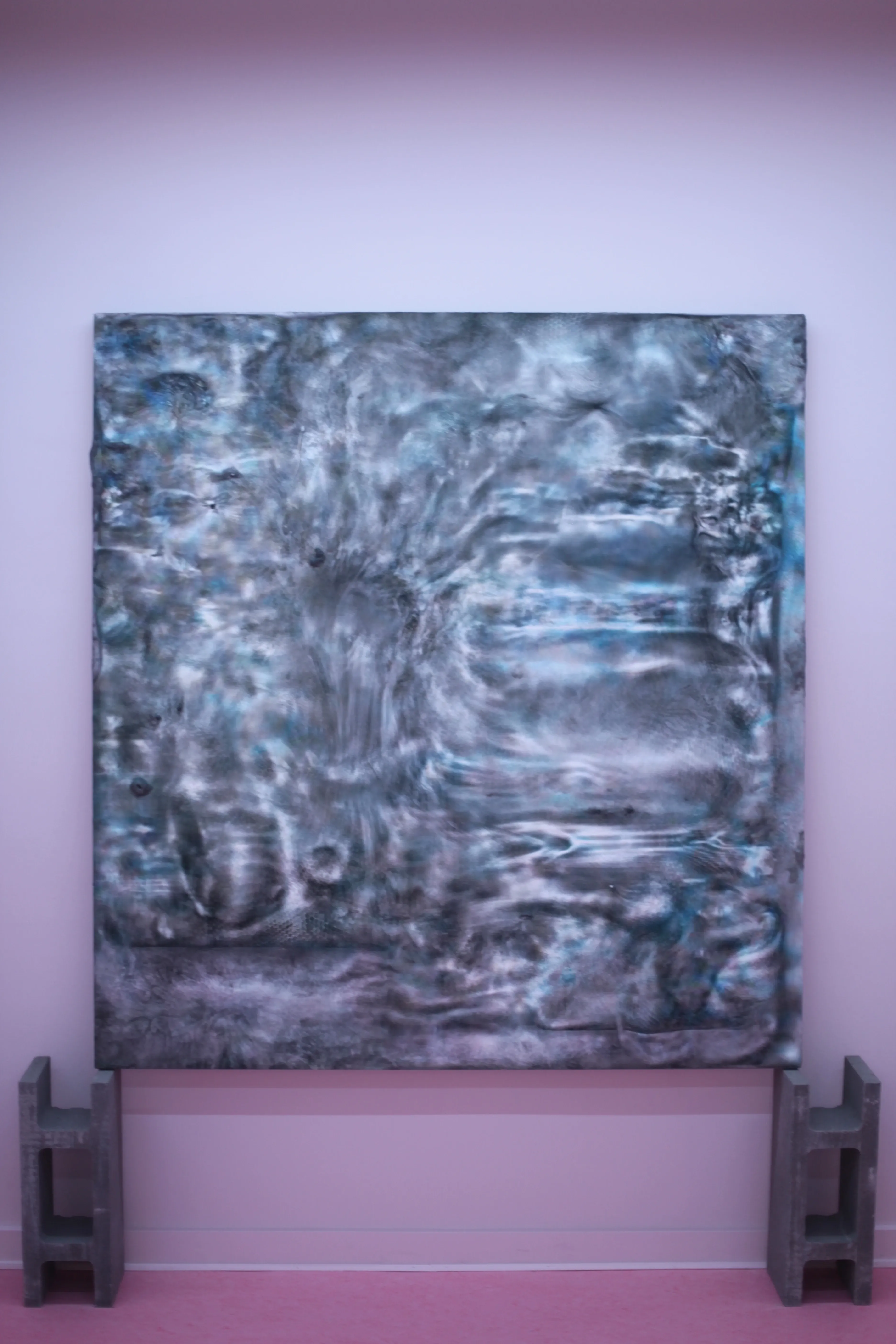 A grey texture painting on two concrete blocks in soft pink room.